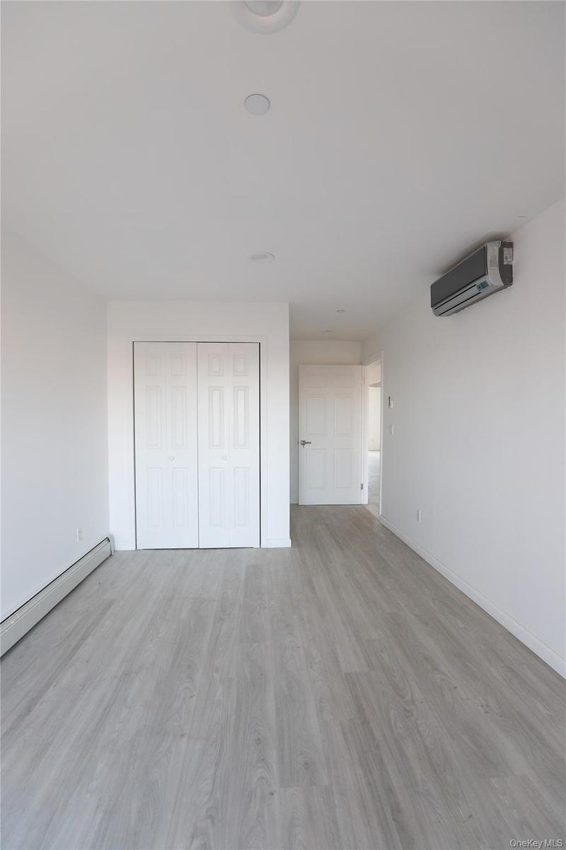 Interior space featuring wood-finish flooring, a wall-mounted ductless mini-split climate control system, recessed ceiling lighting, and a double-door