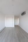 Interior space featuring wood-finish flooring, a wall-mounted ductless mini-split climate control system, recessed ceiling lighting, and a double-door