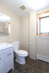 Bathroom featuring a light-toned vanity with an integrated sink, floor-to-ceiling tile walls, stone-finish flooring, and natural wood window trim
