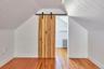 Bonus room featuring a barn door, hardwood / wood-style floors, radiator, lofted ceiling, and wood walls