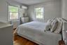 Bedroom with radiator heating unit, dark wood finished floors, and a wall mounted AC