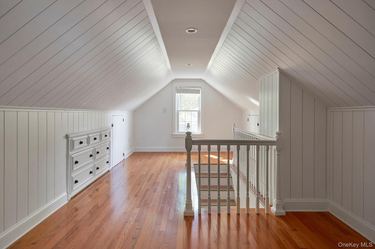 Additional living space with wood walls, light wood finished floors, and vaulted ceiling