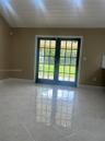 Double French doors featuring multi-pane glass, neutral tile flooring, and a vaulted ceiling with white paneled detail