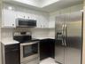 Kitchen featuring white upper cabinetry, dark lower cabinetry, light-toned stone-finish countertops, and stainless steel appliances including a range,