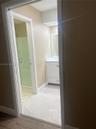 Bathroom featuring a white vanity cabinet with a stone-top integrated sink, a framed wall mirror, and a walk-in shower with a glass door and neutral t