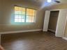 Wood-finish flooring, multi-pane window with blinds, ceiling fan, and built-in closet with louvered doors