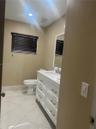 White shaker-style vanity with a stone countertop and rectangular undermount sink, complemented by diagonal-set floor tile and a framed wall mirror
