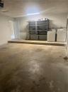 Multi-purpose utility space featuring a concrete floor, laundry hookups, linear overhead lighting, and an access door