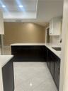 Kitchen featuring dark cabinetry, solid-surface countertops, tile flooring, recessed ceiling lighting, and a skylight
