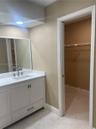 White vanity cabinet featuring a rectangular undermount sink, stone-finish countertop, and brushed-nickel hardware, accompanied by a framed mirror, re