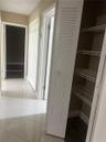 Hallway featuring diagonal-set ceramic tile flooring, louvered closet doors, and interior storage with built-in wire shelving
