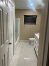 Bathroom featuring diagonal-set tile flooring, vanity with a light-toned countertop, and a shower-tub combination enclosed by a frameless glass door