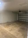 Garage featuring a concrete floor, sectional overhead door, automated garage door opener, and a separate pedestrian access door