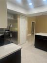 Kitchen featuring dark cabinetry, light-toned solid surface countertops, stainless steel side-by-side refrigerator, recessed lighting, and tile floori