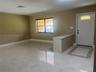 Neutral-toned interior featuring large-format ceramic tile flooring, a built-in counter with a stone-finish top, an exterior door with a decorative tr
