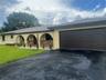 Single-story exterior featuring arched porticos, brick masonry accents, a paved driveway, and an attached multi-car garage