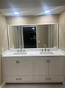 Double vanity featuring white cabinetry, a solid-surface countertop, dual rectangular undermount sinks, polished metal widespread faucets, and a full-