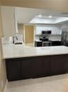 Kitchen featuring white upper cabinetry, dark base cabinetry, stone-surface countertops, recessed ceiling lighting, and stainless steel appliances