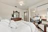 Bedroom interior featuring neutral wall paint, overhead ceiling fan with light fixture, and floor-to-ceiling mirrored sliding closet doors