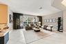 Spacious room featuring light-colored tile flooring, oversized multi-pane windows, neutral wall paint, and a built-in counter surface with stone detai