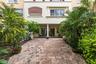 Brick-paved patio featuring a covered loggia, classical columns, and multi-story stucco facade with decorative stonework detailing