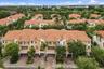 Multi-story residential complex featuring terracotta-style roofing, stucco exterior finish, multiple attached garages, and paver driveways