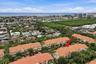 Aerial view of a multi-story residential structure featuring a clay tile roof and a stucco exterior, situated within a coastal landscape
