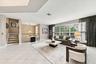 Open-concept interior featuring large-format tile flooring, multi-pane windows, arched window detail, and a staircase with wood treads and a baluster 