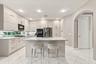 Kitchen featuring flat-panel cabinetry, a central island with a stone countertop, recessed lighting, tile flooring, and stainless steel appliances