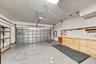 Attached two-car garage featuring a metal overhead door, custom built-in wood cabinetry, integrated pegboard wall organization, and finished concrete 
