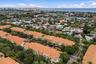 Aerial view featuring Mediterranean-style architecture with clay tile roofs, mature palm trees, and proximity to the coastline