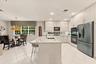 Kitchen featuring flat-panel cabinetry, a stone-surface island with an integrated sink, built-in stainless steel double wall ovens, a recessed microwa