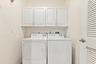 Laundry space featuring white upper cabinetry and a louvered door