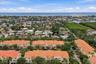 Aerial perspective of a multi-unit complex featuring terra-cotta tile roofs, stucco exterior finish, mature palm trees, and proximity to coastal water