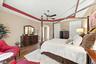 Room featuring tray ceiling with accent molding, wood-finish flooring, and a ceiling fan