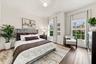 Bedroom featuring wood-finish flooring, an arched window, and a standard rectangular window with multi-pane grids