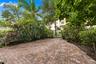 Private patio featuring herringbone-patterned brick pavers, enclosed by high perimeter fencing and lush mature landscaping