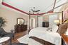 Tray ceiling with accent molding, wood-finish flooring, and a central ceiling fan