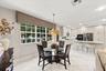 Kitchen featuring flat-panel cabinetry, a stone-surfaced kitchen island, built-in double wall ovens, a tile backsplash, and large-format tile flooring