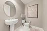 Oval mirror with a metallic frame, white porcelain pedestal sink, polished chrome widespread faucet, and ceramic tile flooring