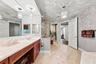 Bathroom vanity featuring a light-toned stone countertop, dual undermount sinks, wood-finish cabinetry, and decorative glass pendant lighting