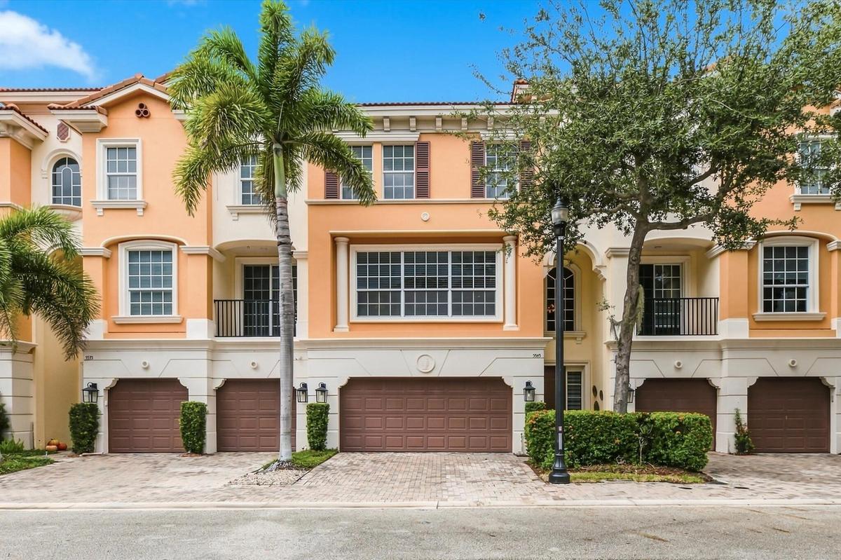 Mediterranean-style exterior featuring a multi-level facade, arched window detailing, wrought iron balcony railings, paved driveway, and attached mult