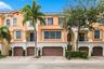 Mediterranean-style exterior featuring a multi-level facade, arched window detailing, wrought iron balcony railings, paved driveway, and attached mult