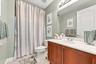 Full bathroom featuring a wood-finish vanity with a light-toned solid surface countertop, an integrated oval basin, a large wall-mounted mirror, and t