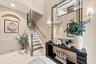 Two-story foyer featuring tile flooring, an arched recessed wall niche, a staircase with wood-finish treads and a white balustrade, and wall-mounted l