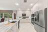 Kitchen featuring flat-panel cabinetry, stone countertops, a stainless steel double wall oven, a stainless steel refrigerator, and recessed lighting