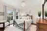 Wood-finish flooring, dual windows with grid detailing, and central overhead lighting fixture
