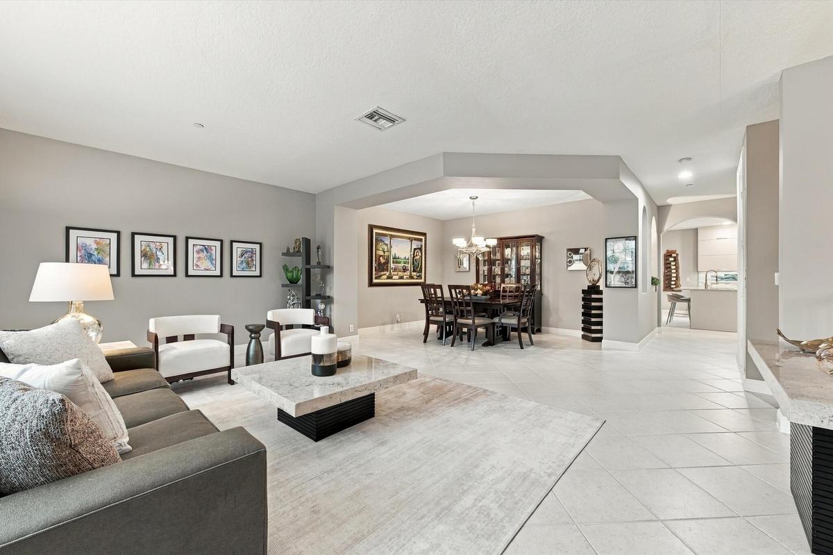 Living area featuring neutral wall tones, large-format tile flooring, recessed lighting, and a distinct architectural recessed ceiling detail