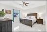 Tray ceiling featuring a central multi-blade ceiling fan with integrated lighting and polished, light-toned tile flooring