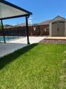 Backyard featuring a covered concrete patio, swimming pool with perimeter fencing, detached storage shed, and horizontal wood-slat privacy fencing